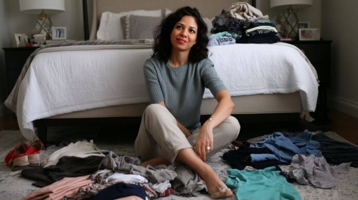 using the one year rule to thin out clothing Isobel surrounded by clothes during a wardrobe declutter session
